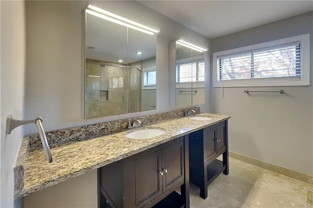 a bathroom with a granite countertop sink and a large mirror