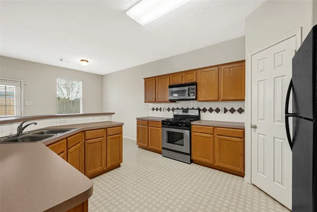 a kitchen with stainless steel appliances granite countertop a refrigerator sink and stove