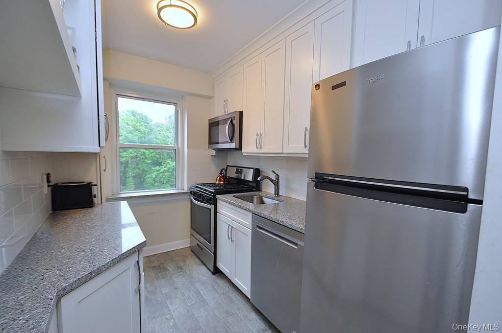 235 Garth Road, Unit A5B Scarsdale, NY 10583 - Photo 7 of 47 a kitchen with a refrigerator a stove a sink a washer and dryer