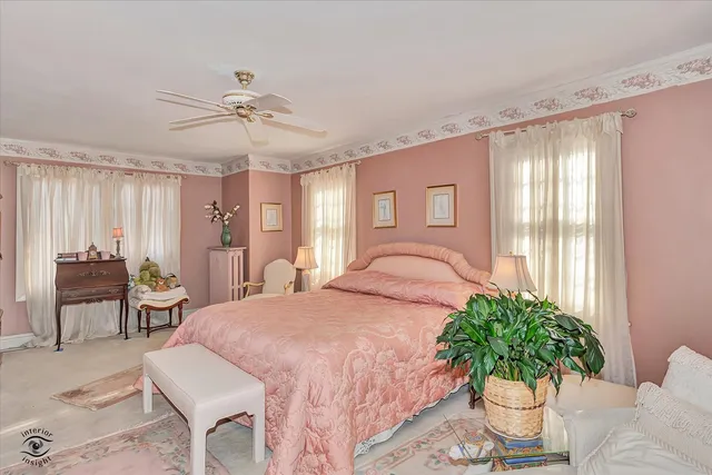 a bedroom with a bed table flowerpot and window