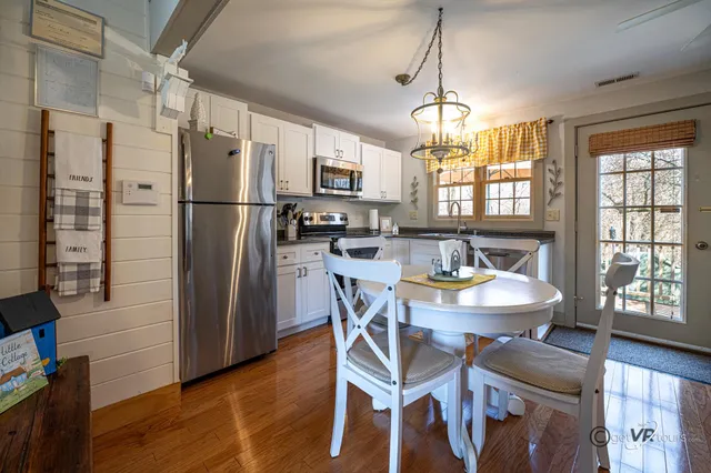 a kitchen with stainless steel appliances a dining table chairs refrigerator and sink