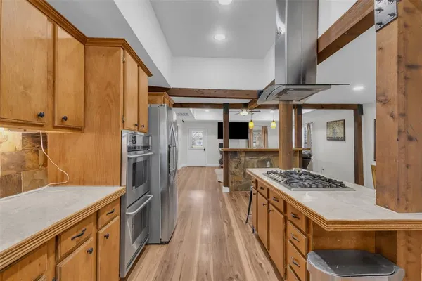 a kitchen with stainless steel appliances kitchen island granite countertop a stove a sink dishwasher and a refrigerator with wooden floor
