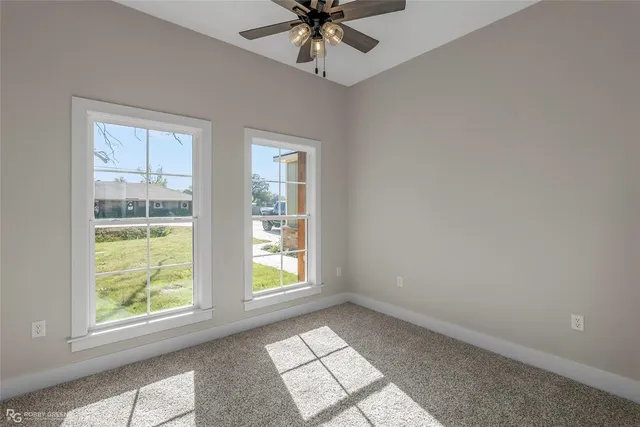 an empty room with windows and ceiling fan
