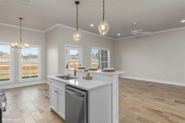 a kitchen with stainless steel appliances granite countertop a sink a window a dining table and chairs