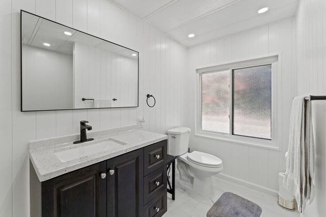 a bathroom with a granite countertop sink a mirror a shower and vanity