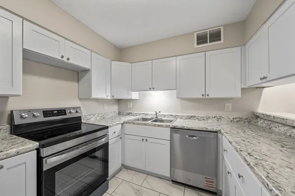 a kitchen with granite countertop a stove sink and cabinets