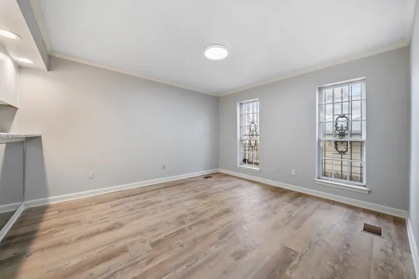 an empty room with wooden floor and windows