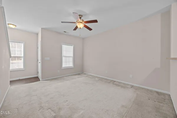an empty room with windows and fan