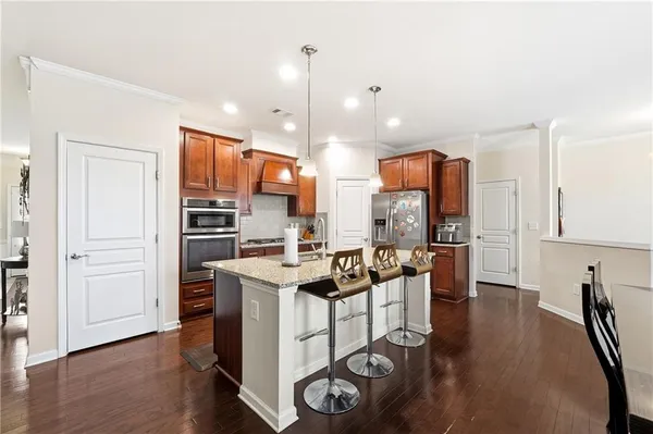 a kitchen with stainless steel appliances kitchen island granite countertop a stove a refrigerator and a dining table with wooden floor