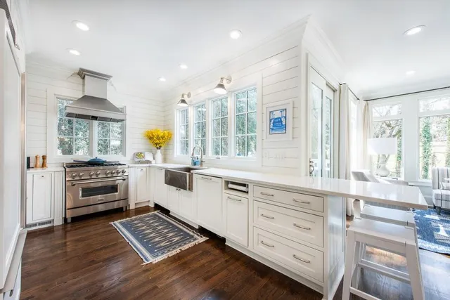 a kitchen with stainless steel appliances a stove a sink and white cabinets with wooden floor