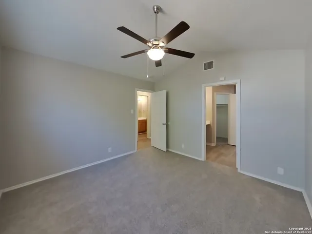 an empty room with closet and a ceiling fan