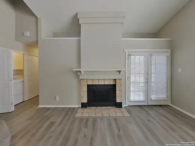 an empty room with wooden floor fireplace and windows