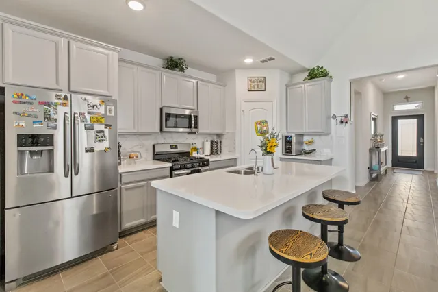 a kitchen with stainless steel appliances a refrigerator a stove a sink a dining table and chairs