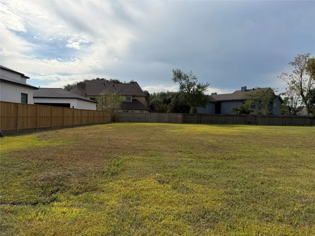 a view of a large pool with lawn chairs under an umbrella