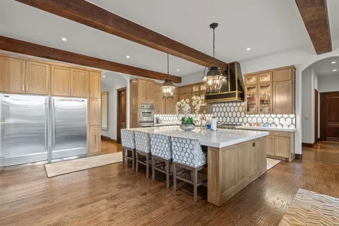 a dining hall with stainless steel appliances granite countertop a kitchen island a refrigerator and a sink
