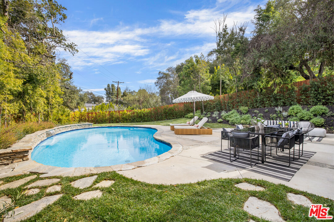 17140 Rancho Street Encino, CA 91316 - Photo 25 of 28 a view of a swimming pool with lawn chairs under an umbrella