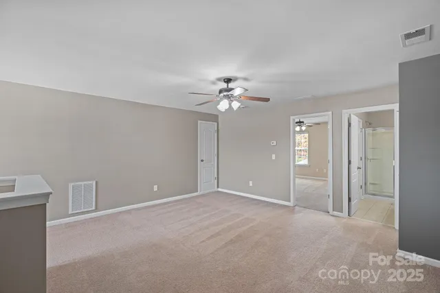 a view of an empty room with a ceiling fan and window