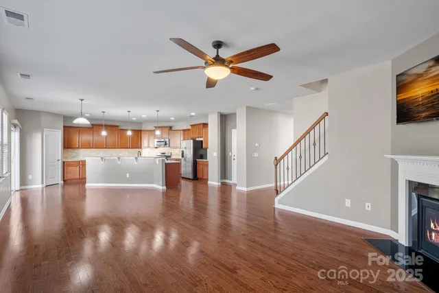 a view of an empty room with wooden floor and a fireplace