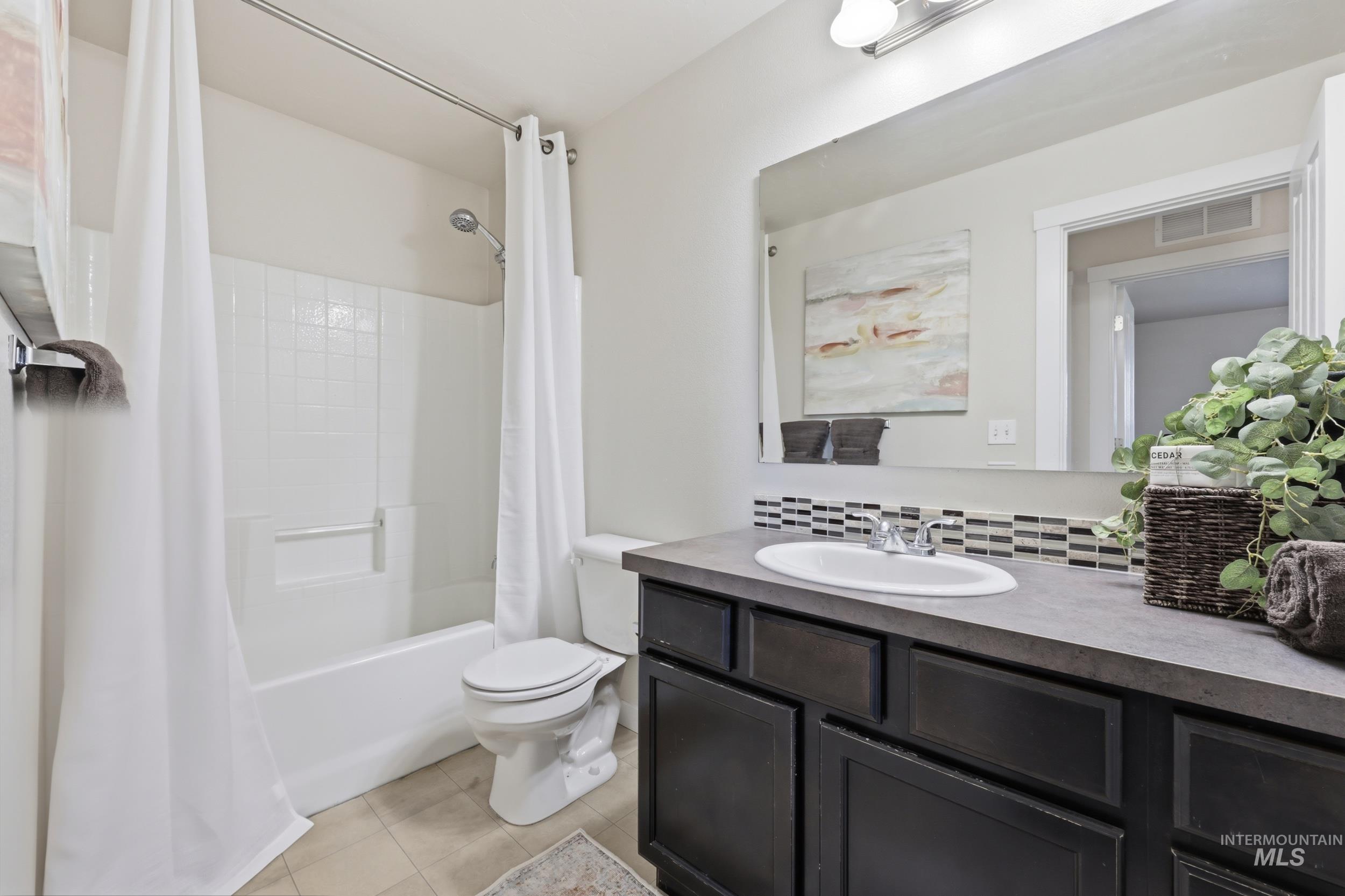 4855 South Chex Way Boise, ID 83709 - Photo 21 of 47 Bathroom featuring a tub/shower combination with white subway tile surround, a built-in vanity with dark cabinetry, a white oval sink, and a decorative tile backsplash