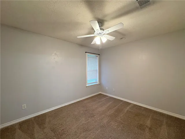 an empty room with a window and ceiling fan