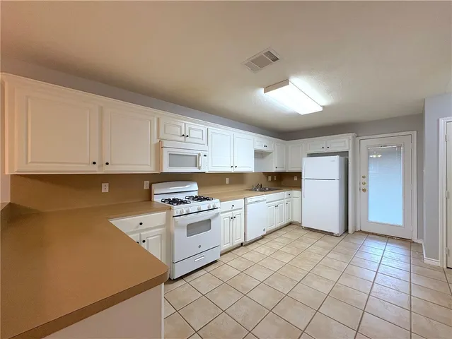 a kitchen with granite countertop white cabinets and white appliances
