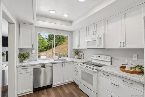 a kitchen with white cabinets white appliances and sink