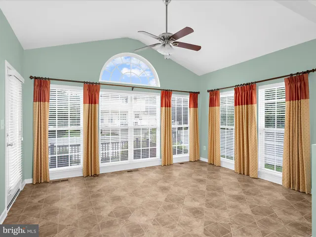 a view of an empty room with window plants and wooden floor