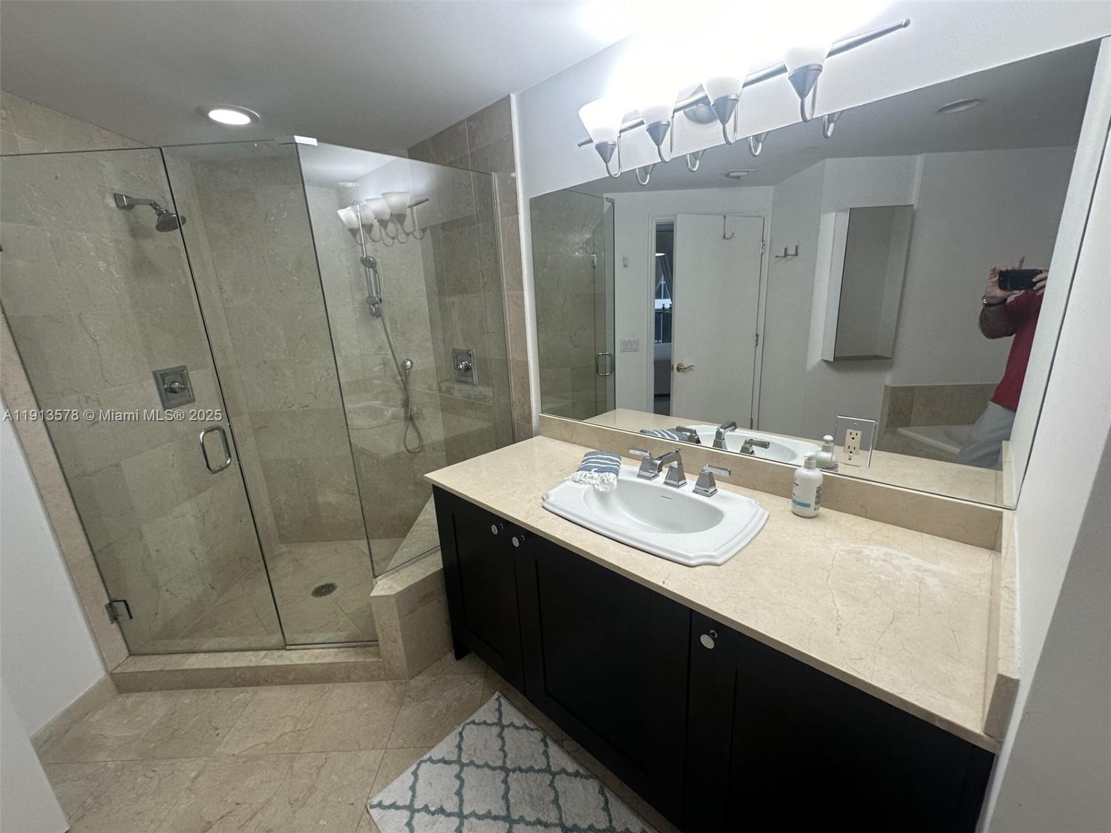 4100 Salzedo Street, Unit 704 Coral Gables, FL 33146 - Photo 18 of 25 a bathroom with a sink a mirror and a shower