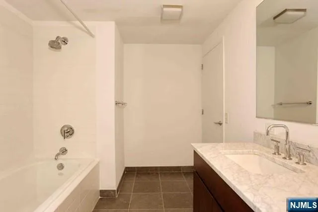 a bathroom with a granite countertop sink a mirror and a bathtub