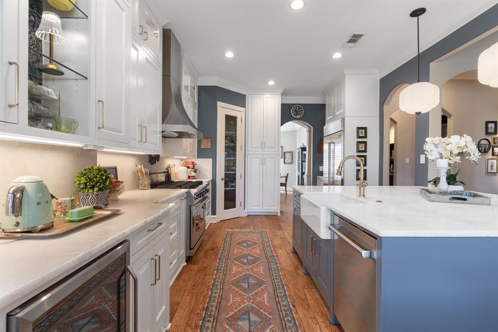 2404 Racheal Drive Heath, TX 75032 - Photo 12 of 40 The chef-inspired kitchen is thoughtfully designed with floor-to-ceiling white custom cabinetry, pot and pan drawers, under-cabinet lighting, soft gold hardware, and illuminated glass-front upper cabinets to showcase your most treasured pieces. The cabinets are accented with designer wallpaper from Rifle Paper Co.