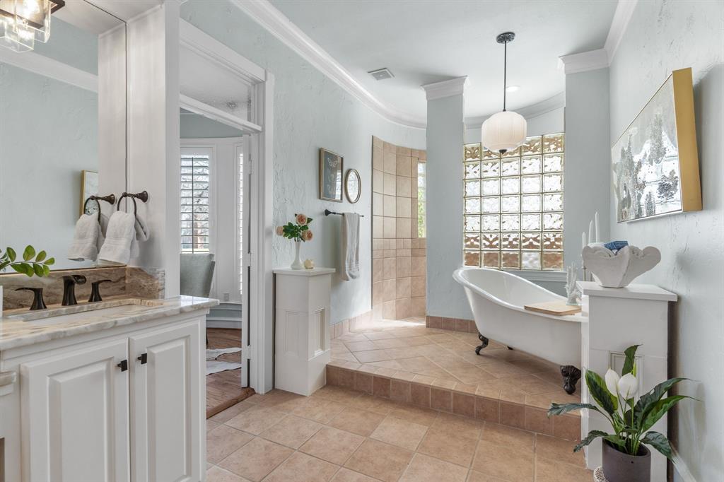 2404 Racheal Drive Heath, TX 75032 - Photo 21 of 40 The primary en suite bathroom is a study in elegance, with tile floors and two stately pillars framing the raised platform that holds a freestanding clawfoot bathtub, illuminated by an Anthropologie pendant overhead.