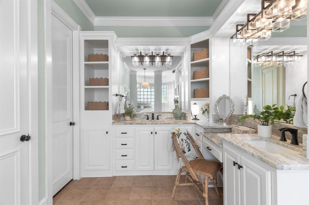 2404 Racheal Drive Heath, TX 75032 - Photo 22 of 40 The substantial built-in vanity is a showpiece, boasting white custom cabinetry that extends toward the ceiling, black hardware, marble countertops, dual undermount sinks, a built-in makeup desk, and designer lighting.