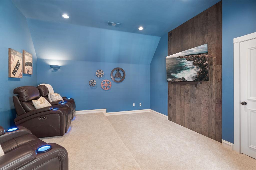 2404 Racheal Drive Heath, TX 75032 - Photo 27 of 40 The media room is designed for an immersive, theater-like experience, featuring plush carpeting and tiered seating with four reclining media chairs that are included with the home. Theatre-style wall sconces set the ambiance, while a striking wood-plank feature wall serves as the backdrop for the flat-screen TV, which will convey.