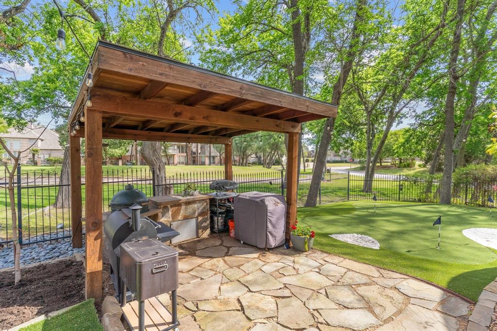 2404 Racheal Drive Heath, TX 75032 - Photo 35 of 40 A beautifully crafted built-in wood pergola shelters an outdoor kitchen crafted from natural stone, complete with a Green Egg smoker that conveys with the home, allowing for grilling outdoors and entertaining under the string lights.