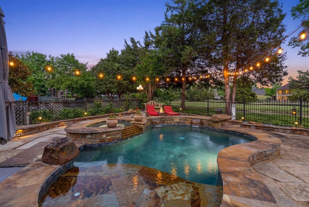 2404 Racheal Drive Heath, TX 75032 - Photo 4 of 40 The heated pool and spa, beautifully crafted with natural stone accents, features cascading waterfalls, a 12-inch deep sun shelf ideal for lounging or for young swimmers, and a 6-foot-deep end complete with a built-in stone bench for added comfort.