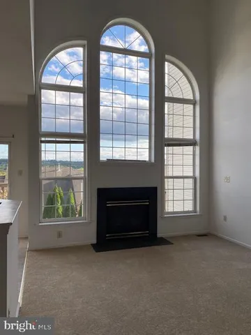 an empty room with windows fireplace and wooden floor