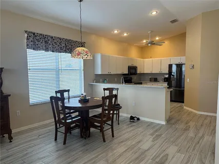 a kitchen with kitchen island a dining table chairs stainless steel appliances and cabinets