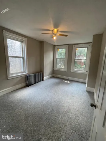 an empty room with windows and fan