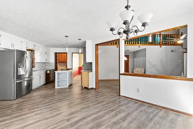 an empty room with wooden floor fireplace and windows