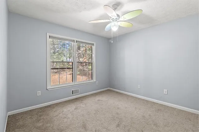 a view of an empty room with a window and a ceiling fan