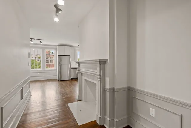 a view of a kitchen with wooden floor electronic appliances and cabinets