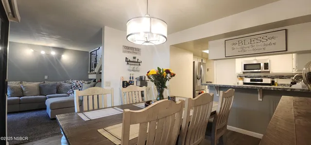 a living room with furniture kitchen view and a chandelier