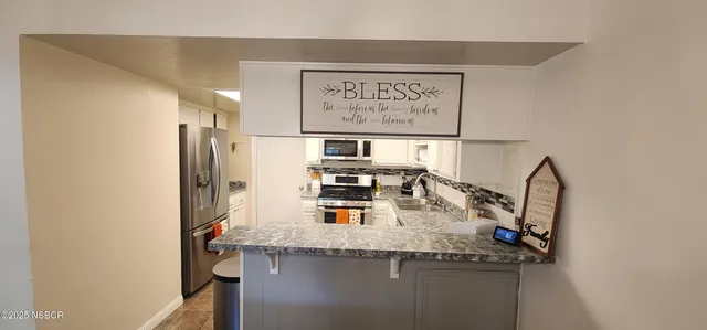 a kitchen with stainless steel appliances granite countertop a sink and a refrigerator