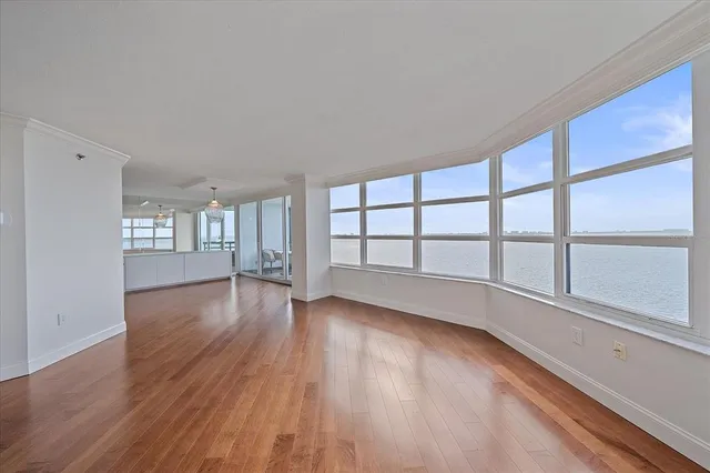 a view of an empty room with a window and wooden floor