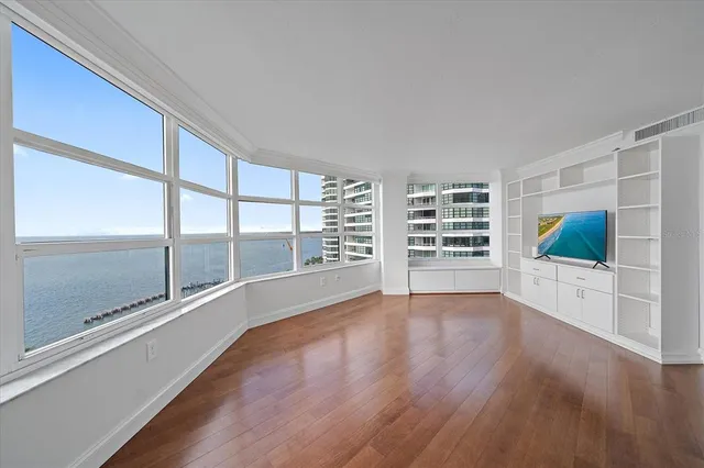 a view of empty room with wooden floor and fan