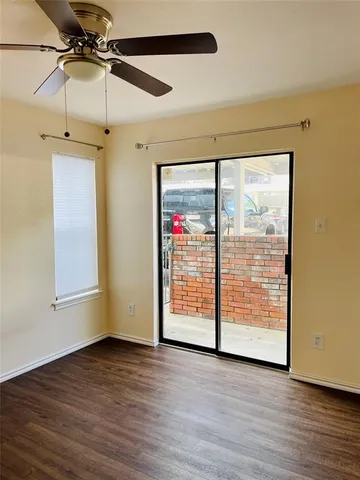 a view of an empty room with wooden floor and fan
