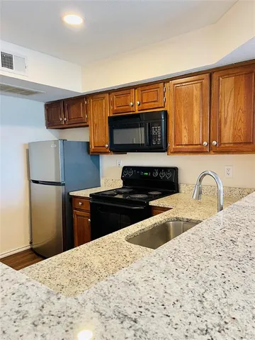 a kitchen with granite countertop a refrigerator and a sink