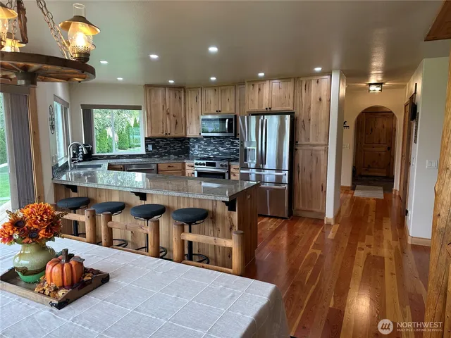a kitchen with stainless steel appliances granite countertop a refrigerator a sink a stove and a wooden cabinets