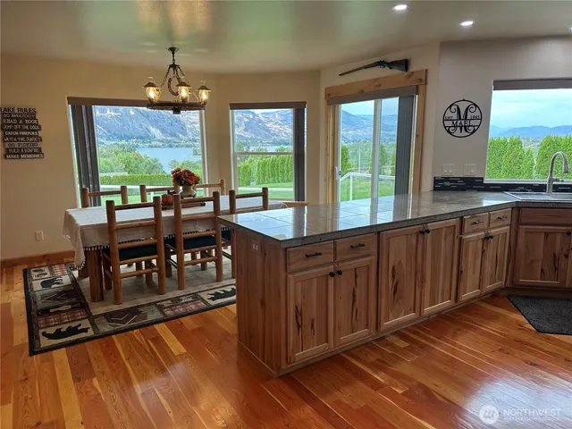 a kitchen with kitchen island granite countertop wooden floors and a view of living room