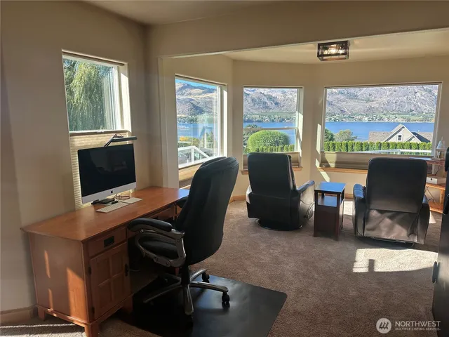 a view of a workspace with furniture and a window